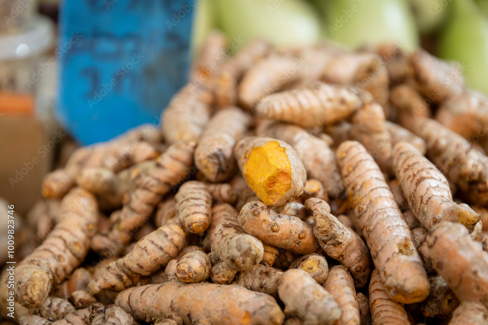 A pile of turmeric roots heaped on a stall for sale. One of them is cut open. A pile of turmeric roots heaped on a stall for sale. One of them is cut open.