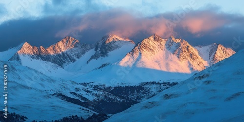 Majestic snow-capped mountains illuminated by soft sunlight under a cloudy sky.