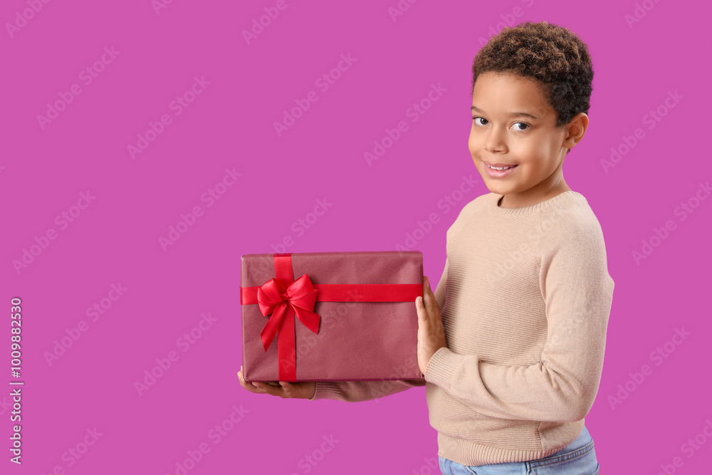 Little African-American boy with Christmas gift on purple background Little African-American boy with Christmas gift on purple background