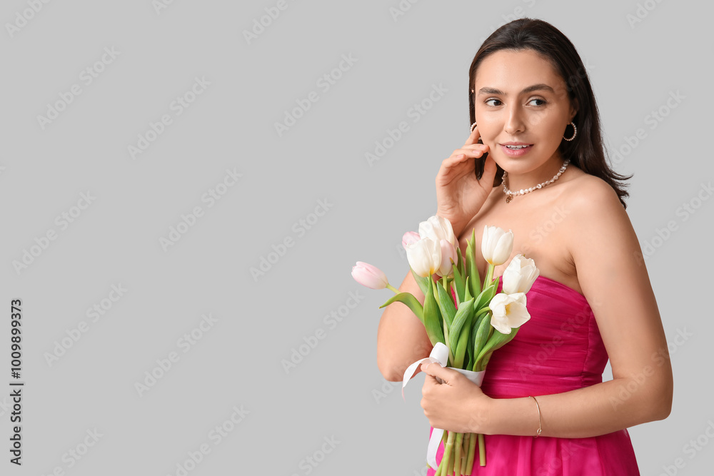 Beautiful young woman with bouquet of tulips on grey background. International Women's Day Beautiful young woman with bouquet of tulips on grey background. International Women's Day