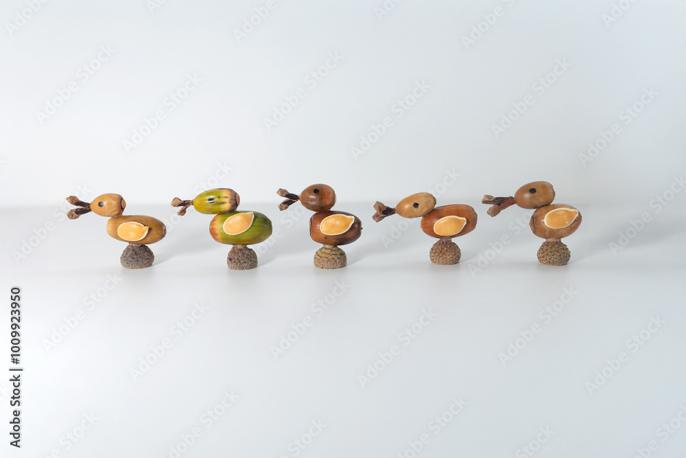 Collection of five acorn ducks arranged in a row. Crafted from acorns, twigs, and natural materials. One green duck, four brown ducks. Creative autumn crafts, perfect for seasonal decor Collection of five acorn ducks arranged in a row. Crafted from acorns, twigs, and natural materials. One green duck, four brown ducks. Creative autumn crafts, perfect for seasonal decor