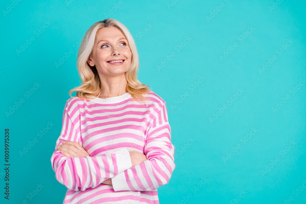Portrait of optimistic senior person with wavy hairdo wear striped pullover arms folded look empty space isolated on blue color background Portrait of optimistic senior person with wavy hairdo wear striped pullover arms folded look empty space isolated on blue color background