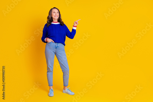 Full length photo of lovely pensioner lady look point empty space dressed stylish blue knitted garment isolated on yellow color background