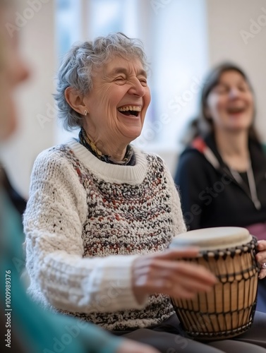 A group of women are gathered in a community center, joyfully participating in a drumming session and laughing together. Music as hobby.