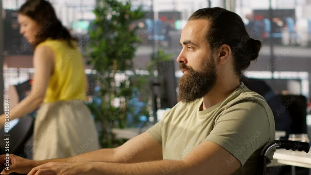 System administrator with disability in inclusive workspace training machine learning models. IT specialist with paraplegia monitoring and maintaining company systems, camera A System administrator with disability in inclusive workspace training machine learning models. IT specialist with paraplegia monitoring and maintaining company systems, camera A