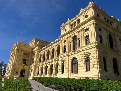 Fotografi Foto da vista panorâmica do Museu do Ipiranga em São Paulo, Brasil, com o edifício histórico, jardins e fontes sob um céu azul claro