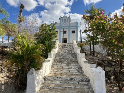 Paisagem histórica em Goiás, Goiás, Brasil, com uma torre de igreja, palmeiras altas e escadaria de pedra em um morro sob um céu azul claro. Captura o charme deste local colonial. photo