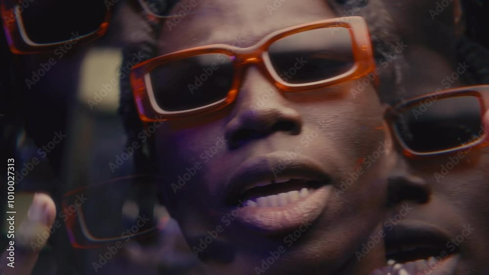 Kaleidoscopic effect of expressive Black rapper with dreadlocks wearing trendy orange sunglasses and gold chain necklace gesturing and performing hip-hop song on camera Kaleidoscopic effect of expressive Black rapper with dreadlocks wearing trendy orange sunglasses and gold chain necklace gesturing and performing hip-hop song on camera