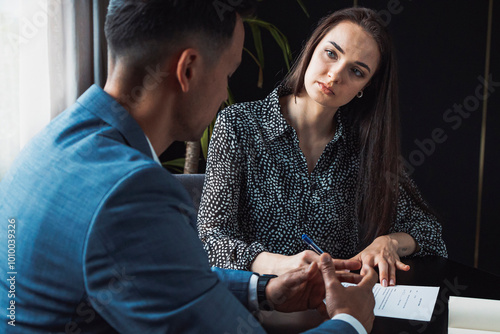 Obraz na plátně Two business people in business clothes are sitting in an office looking at a contract