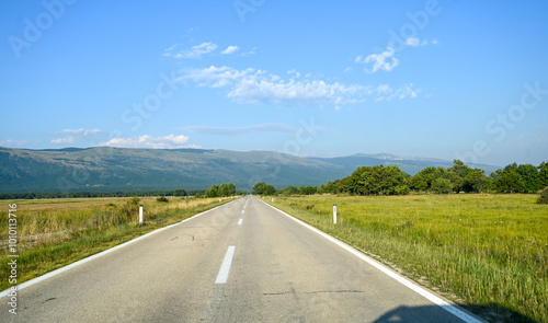 A long straight road in a field. Driving a car in nature. Drivers view on asphalt road in field in summer. 