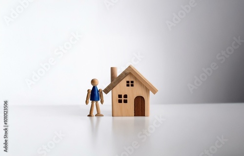 A wooden figurine of a person standing in front of a small wooden house.