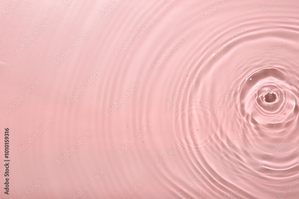 Obraz premium Rippled surface of clear water on pink background, top view