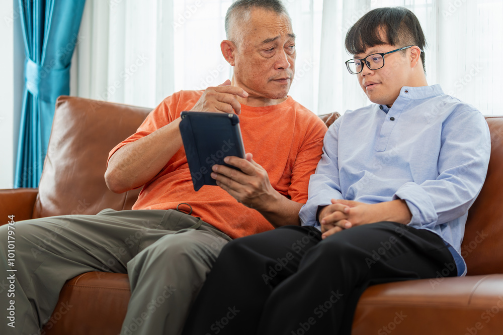 Fototapeta premium Asian man listen to senior man talking seated on sofa at home, speaking spend time together at home