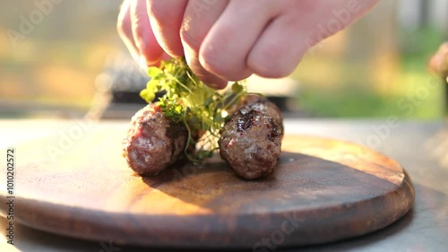 Cook puts juicy cutlets and kebabs on board and sprinkle with fresh herbs and herbs. Delicious picnic food outdoors. lunch for family or friends. party with the preparation of fresh juicy steaks
