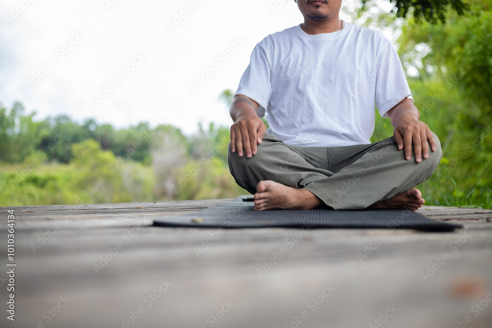 A man is sitting on a mat on a wooden bridge A man is sitting on a mat on a wooden bridge