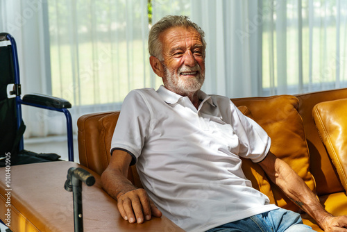 A Caucasian elderly man is sitting smiling and happy in a nursing home. The living room is beautiful.
