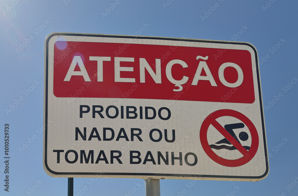 No swimming sign displaying warning in portuguese on blue sky background No swimming sign displaying warning in portuguese on blue sky background