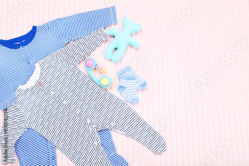 Baby clothes with toys on pink background photo