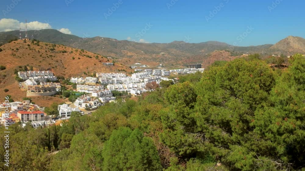 View from Gibralfaro hill in Málaga, Spain, with whitewashed houses nestled in the foothills surrounded by green trees and a clear blue sky, highlighting the Mediterranean charm View from Gibralfaro hill in Málaga, Spain, with whitewashed houses nestled in the foothills surrounded by green trees and a clear blue sky, highlighting the Mediterranean charm