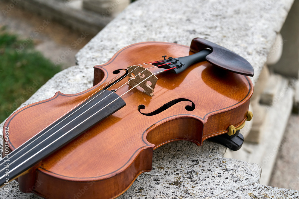 Φωτογραφία Violino appoggiato su un muretto di granito marmo bianco con il pizzico poggiato sotto alla cassa  armonica