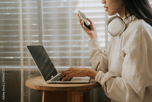 Woman working from home, using laptop and phone  photo