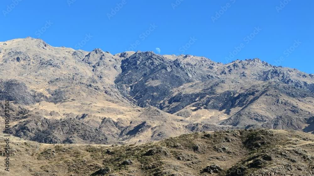 Clear blue sky with moon over rugged arid peaks of the Andes. Tafí del Valle, Tucumán, Argentina. Clear blue sky with moon over rugged arid peaks of the Andes. Tafí del Valle, Tucumán, Argentina.