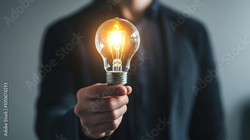 Glowing Lightbulb in Businessman's Hand Symbolizing Innovation and photo
