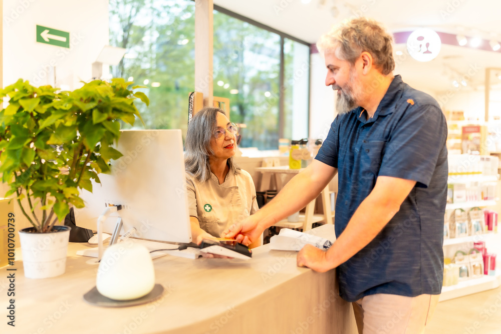 Pharmacist talking to a client while paying on the counter Pharmacist talking to a client while paying on the counter