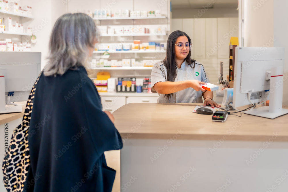 Saleswoman attending a woman in the counter of a pharmacy Saleswoman attending a woman in the counter of a pharmacy