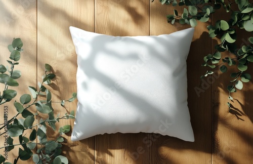 White pillow mockup on wooden floor with sunlight and green leaves. photo