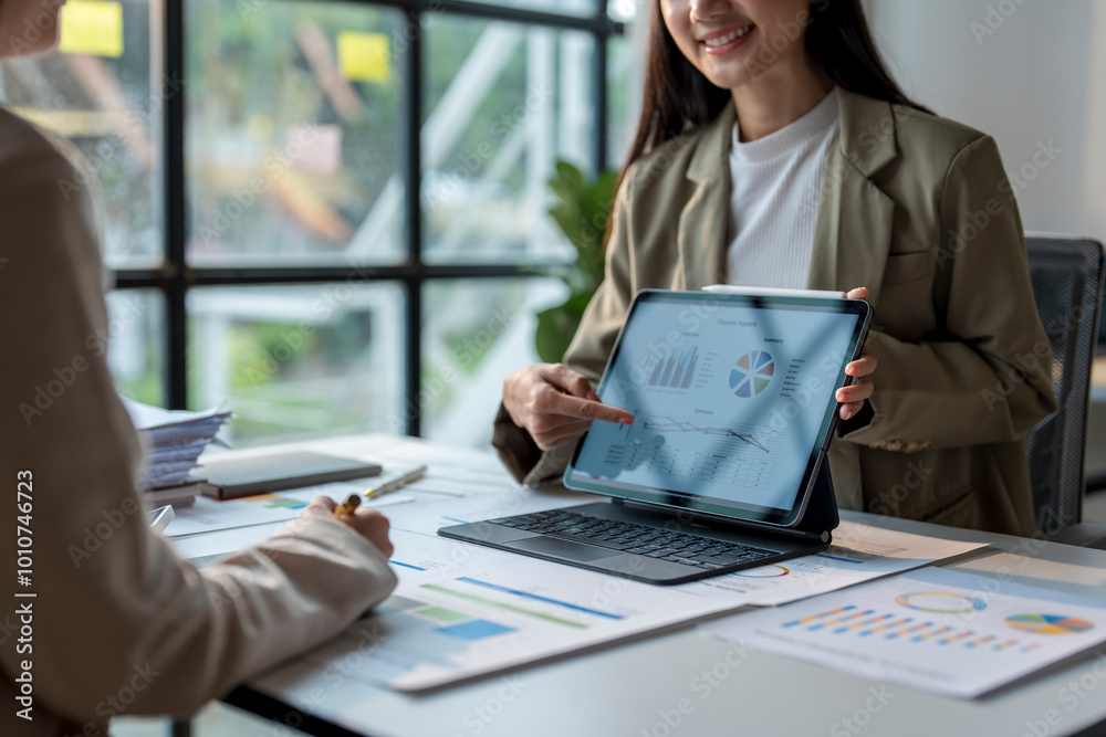 Businesswoman showing financial data on tablet to colleague during meeting Businesswoman showing financial data on tablet to colleague during meeting