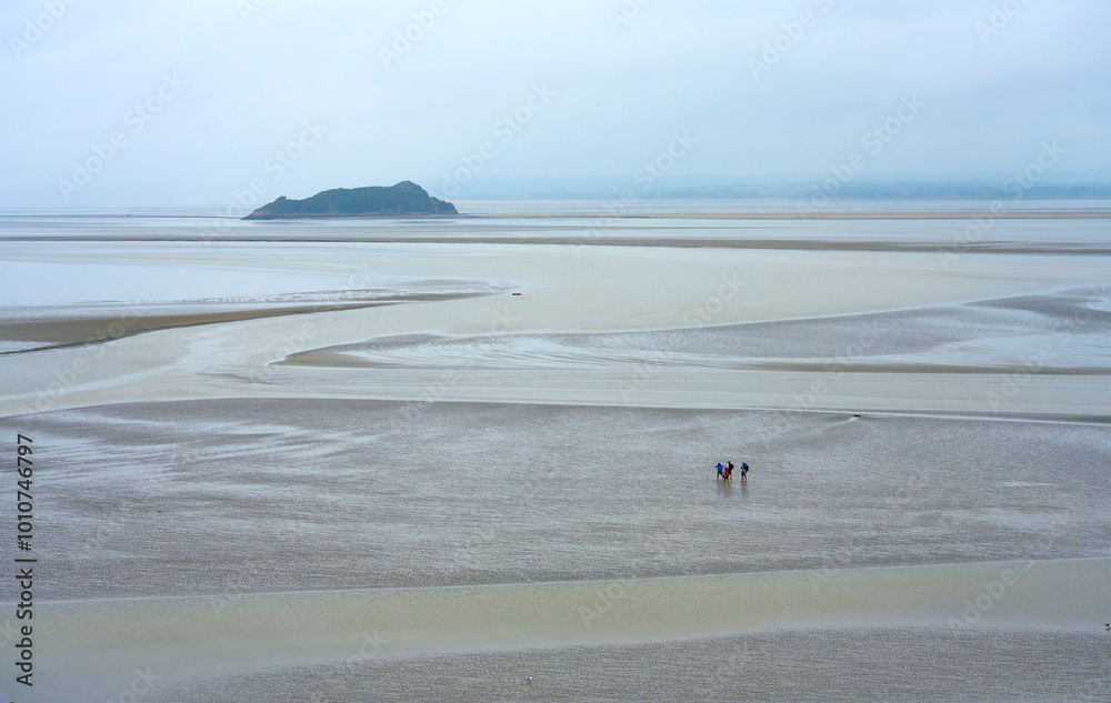 Φωτογραφία group of people hiking in the wadden sea in front of Le Mont saint Michel at low