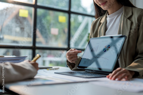 Businesswoman pointing at tablet showing financial data to her coworker during a meeting