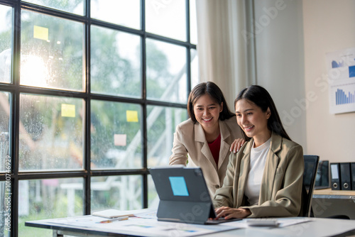 Two young businesswomen working on a project using a laptop in their office