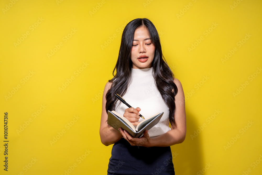 A woman is writing in a notebook with a pen