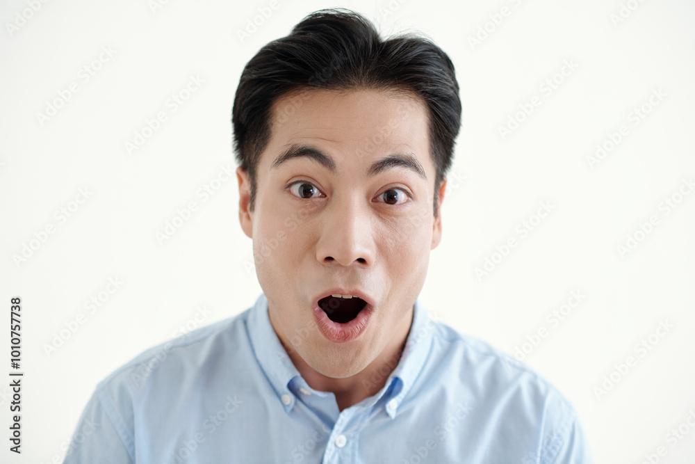 Surprised young man looking at camera against white background Surprised young man looking at camera against white background