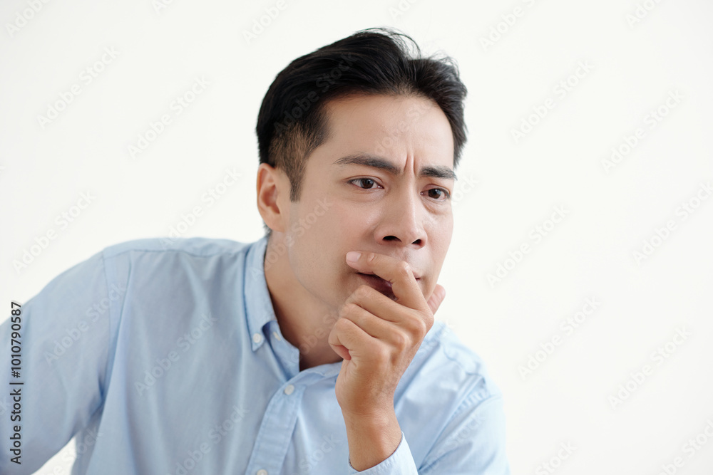 Asian man sitting with pensive expression on white background Asian man sitting with pensive expression on white background