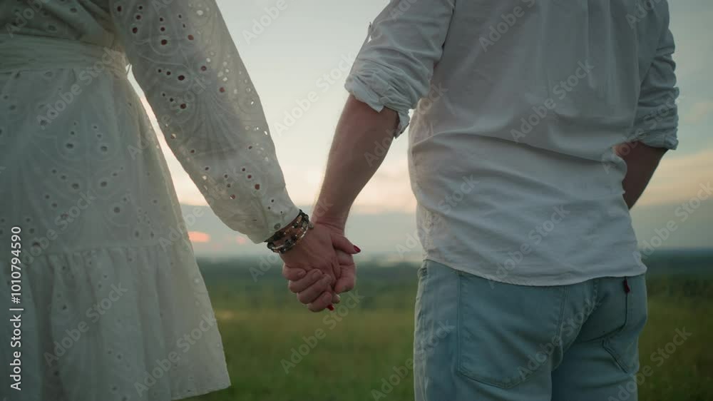 A close-up of lovers holding hands gently, with the woman s hand adorned with beaded bracelets and red nails. The soft sunlight illuminates the scene, creating a warm and intimate atmosphere A close-up of lovers holding hands gently, with the woman s hand adorned with beaded bracelets and red nails. The soft sunlight illuminates the scene, creating a warm and intimate atmosphere