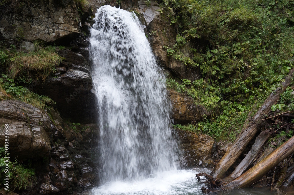 Naklejka premium A beautiful waterfall in a mountainous and wooded area. Mendelikha Park.