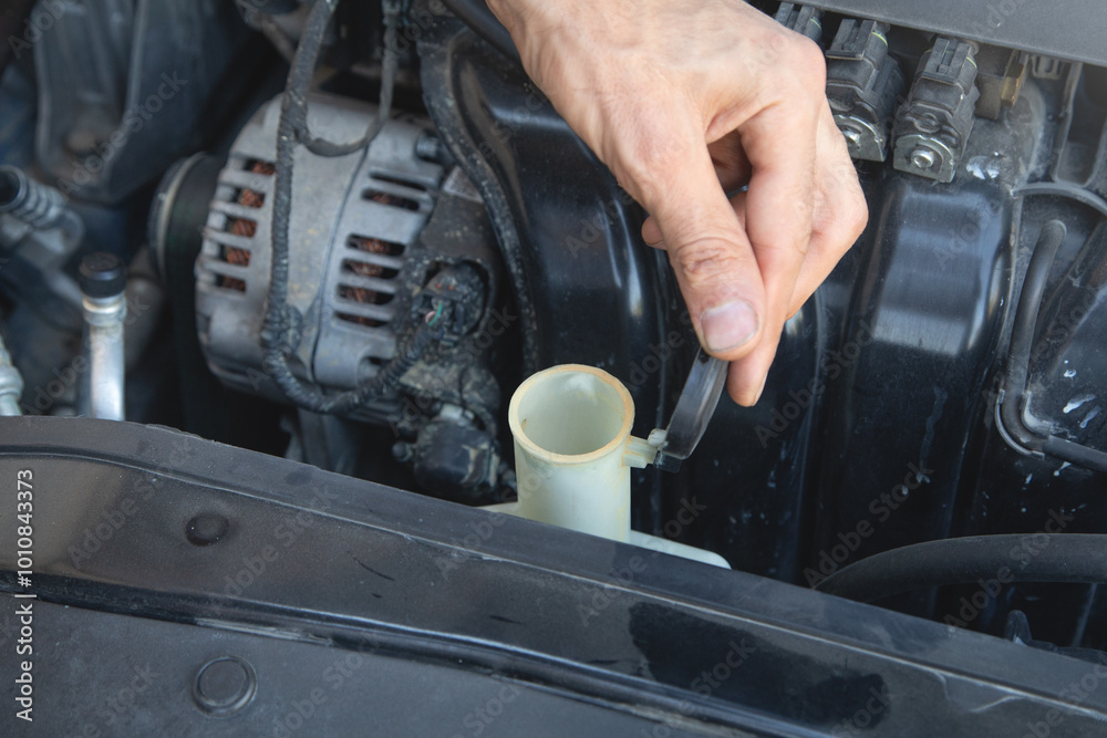 Man checking the windshield washer fluid of a car. Man checking the windshield washer fluid of a car.