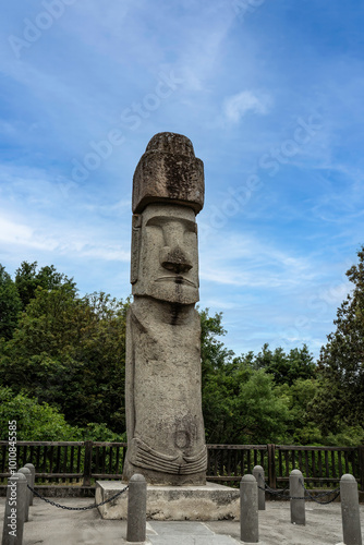 Moai statue in Vitorchiano, Italy created by Rapa Nui descendants. Tall stone sculpture carved from local peperino stone stands majestically against a backdrop of blue skies and greenery. photo