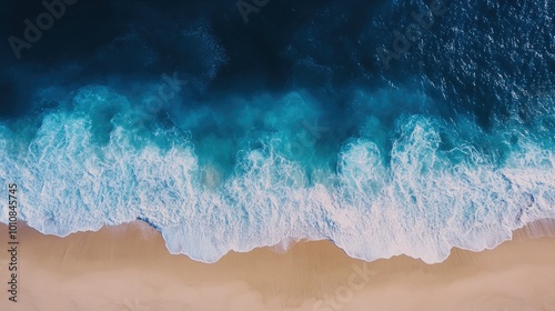 Aerial top-down view of blue ocean waves meeting a sandy beach in Vietnam, creating a serene and picturesque natural backdrop for summer.