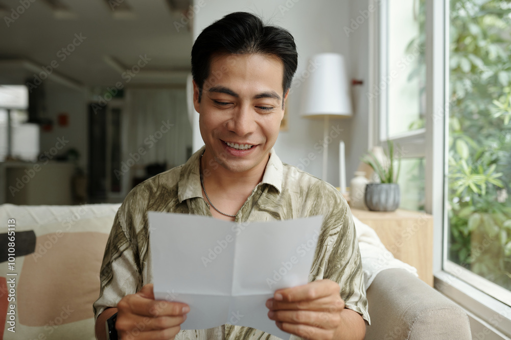 Man sitting on sofa and reading letter with good news Man sitting on sofa and reading letter with good news
