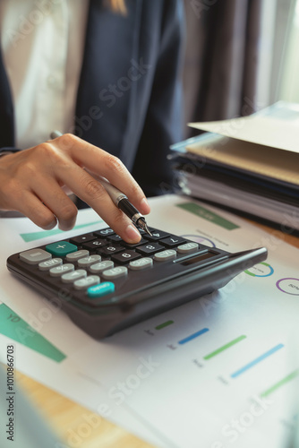 Accountant using calculator with financial documents on desk office.