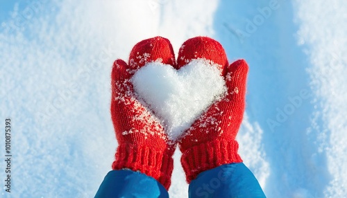 hands in knitted mittens with heart of snow in winter day 