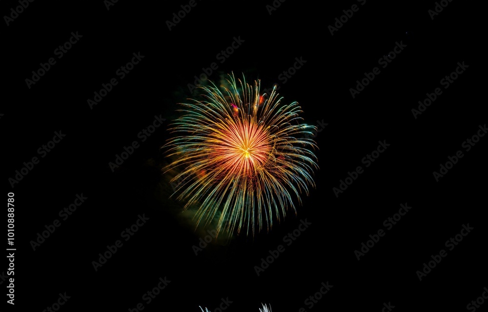 A single firework explodes in the night sky, creating a burst of yellow, red, and green light. A single firework explodes in the night sky, creating a burst of yellow, red, and green light.