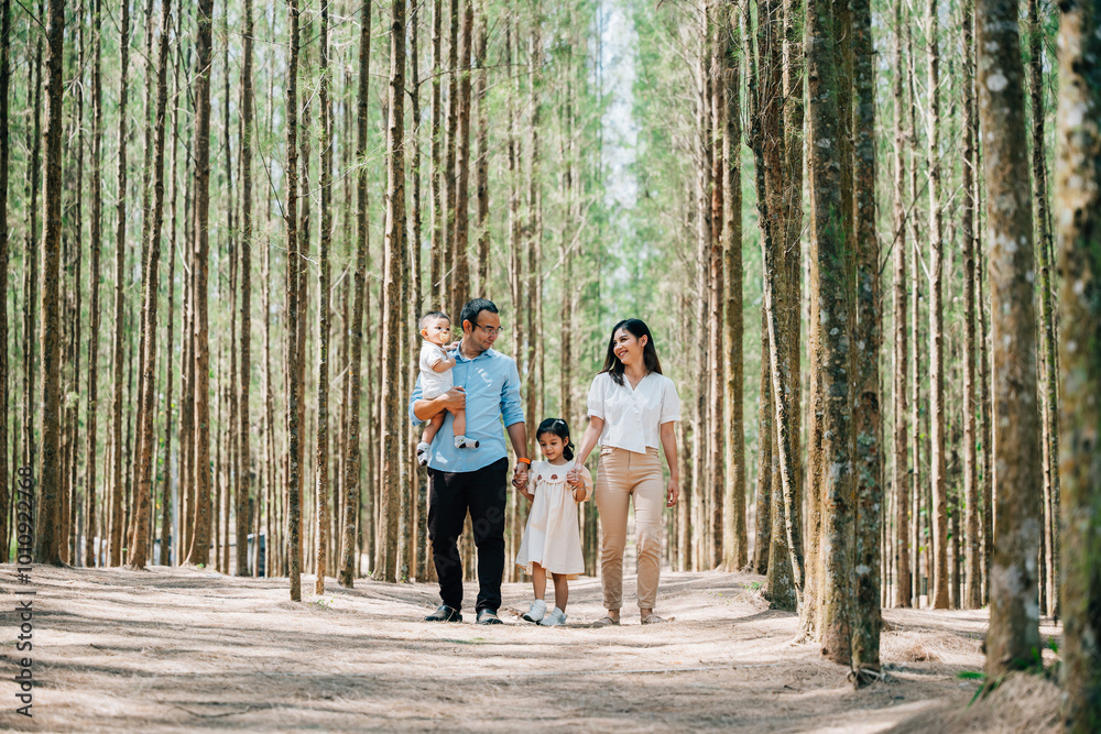 Fototapeta premium A happy Asian family walking through a park in the spring, with their baby in a stroller and their daughter holding their hands, Happy family day