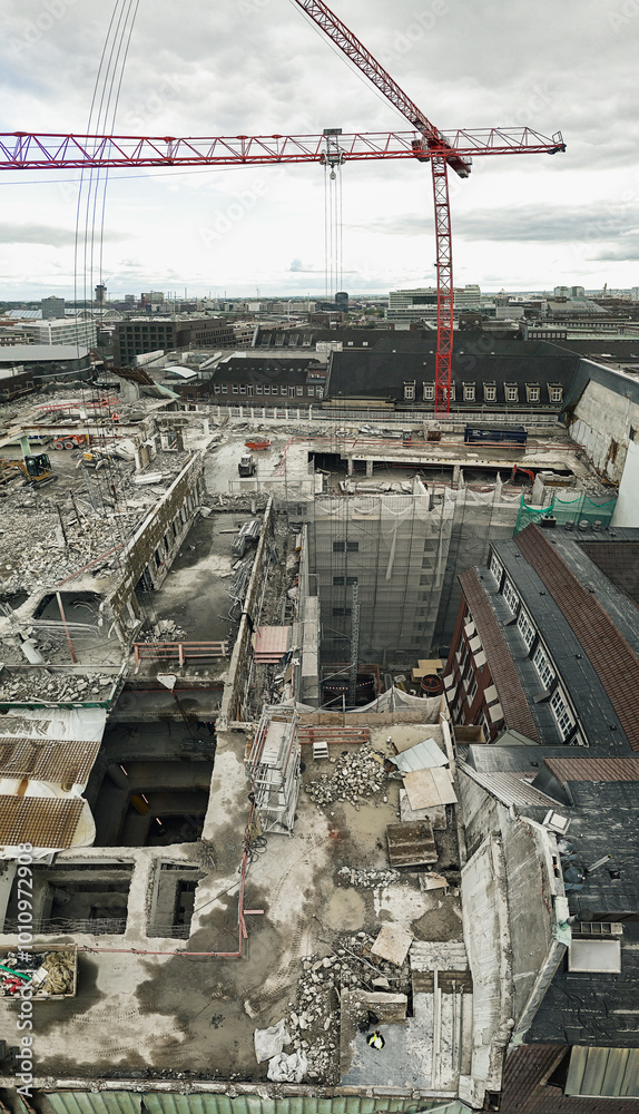 Fototapeta premium This depicts a construction site with a large red crane and partially demolished buildings. The site appears to be in an urban area, with ongoing demolition or redevelopment work.