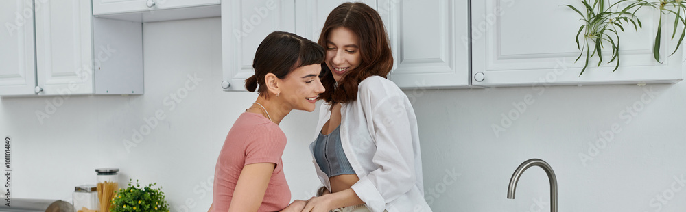 A young lesbian couple shares a tender embrace in their kitchen, their love and connection evident in their morning glow. A young lesbian couple shares a tender embrace in their kitchen, their love and connection evident in their morning glow.
