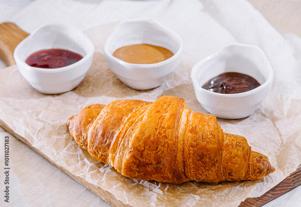 Freshly baked croissant with bowls of jam and peanut butter for breakfast Freshly baked croissant with bowls of jam and peanut butter for breakfast